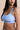 Woman wearing a light blue sports bra with 'Habits' branding on a beige background