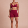 Red athletic outfit with a sports bra and shorts on a beige background