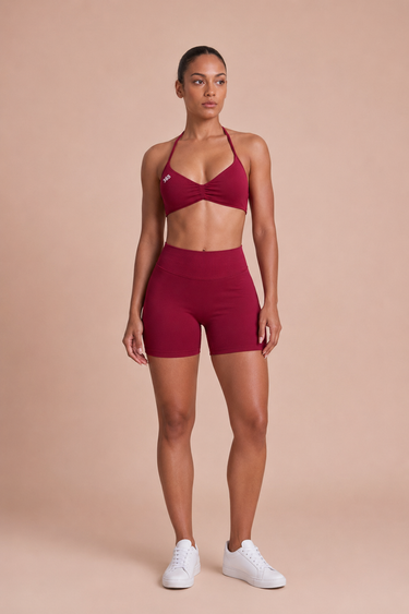 Red athletic outfit with a sports bra and shorts on a beige background