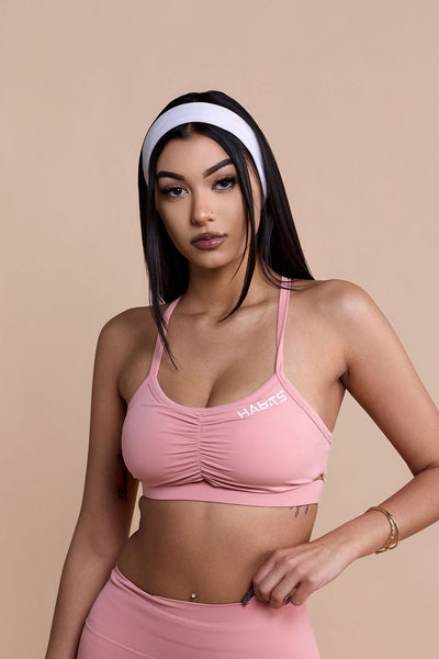 Woman wearing a pink sports bra and leggings set on a beige background