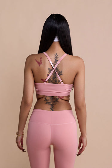 Person wearing a pink sports bra and leggings set on a beige background